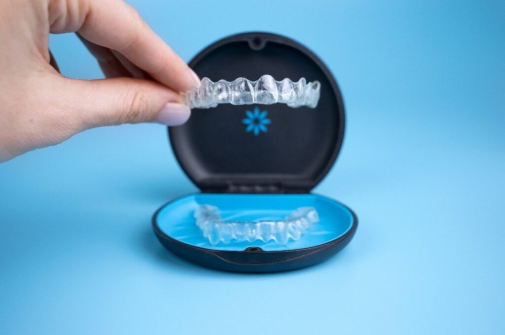 Eine Frau hält eine Invisalign Zahnschiene in der Hand